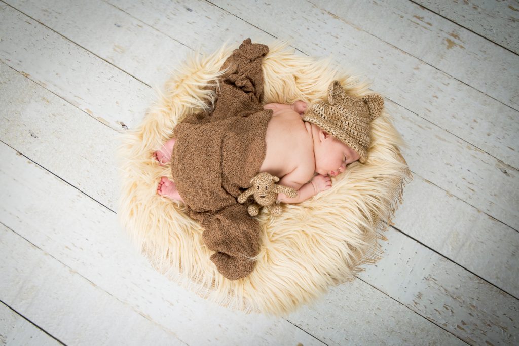 Newborn shoot Jolie op witte schaal met kleedje en met een mutsje op en een beertje erbij