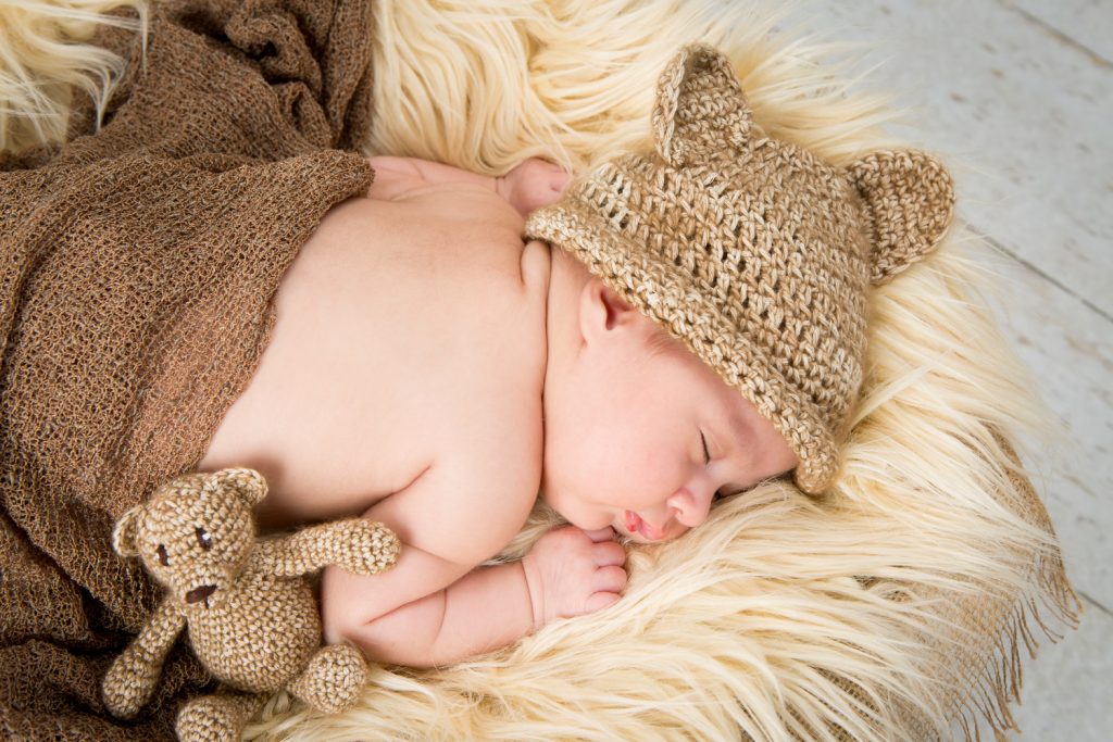 Newborn shoot Jolie op witte schaal met kleedje en met een mutsje op en een beertje erbij