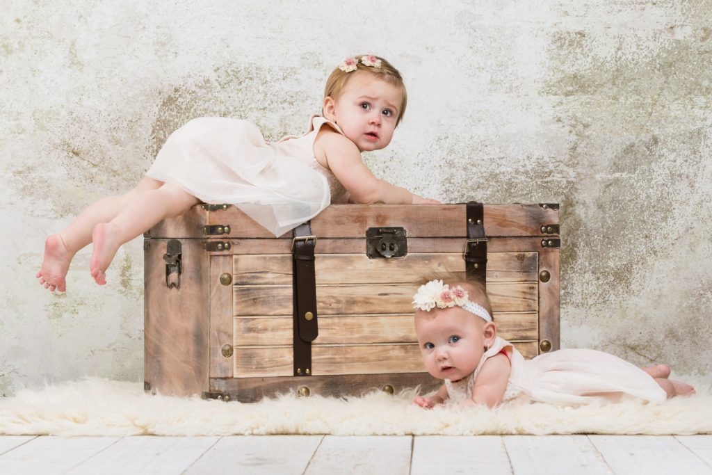 Baby fotoshoot Chelsea en Gianna met witte kleiding aan en als prop een kist
