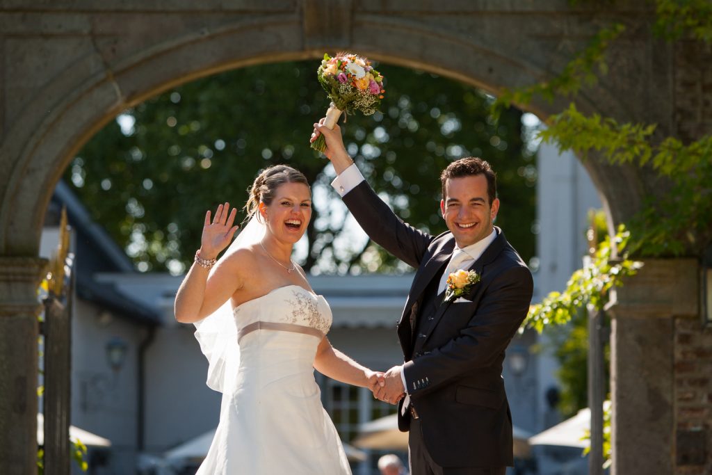 Bruidsreportage William en Valerie zwaaien vanuit de ingang van Kasteel Groot Buggenum