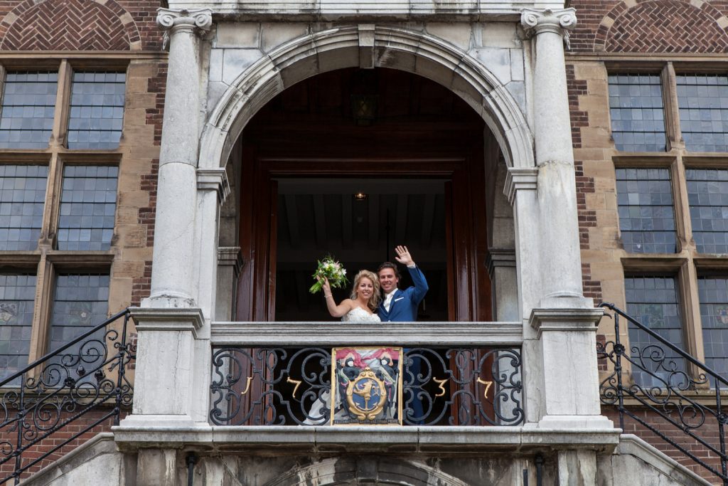Bruidsreportage Robin en Willem na de ceremonie zwaaien vanaf het stadhuis