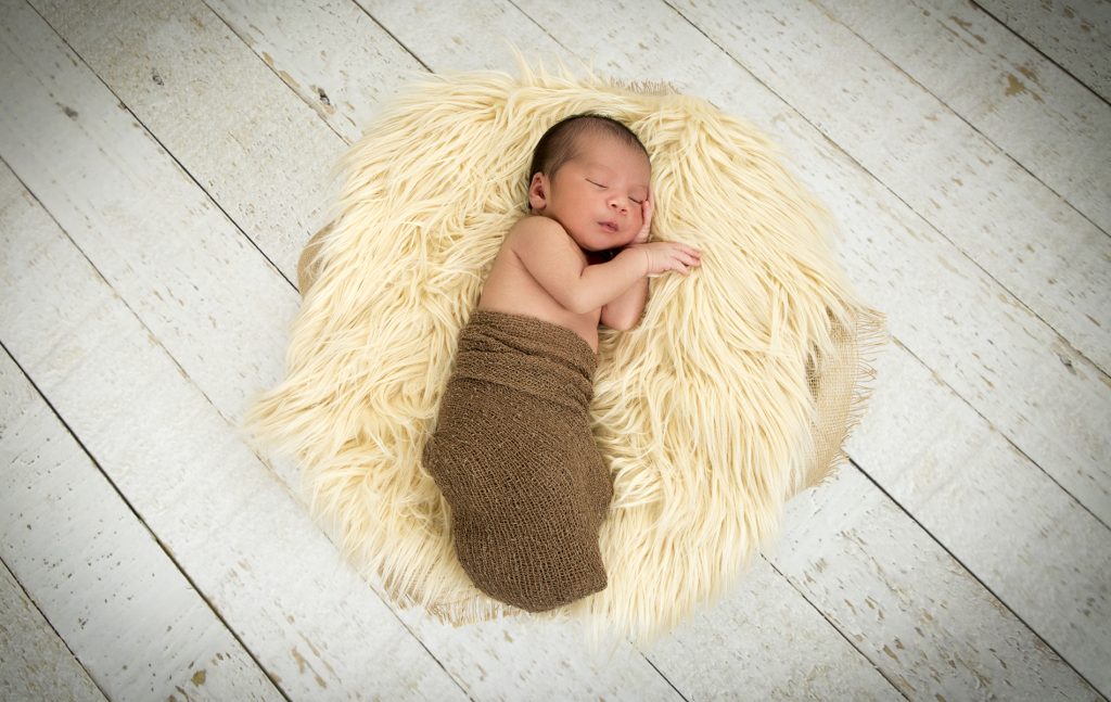 Newborn shoot baby Rumi op wit dekentje gewikkeld in een bruine wrap